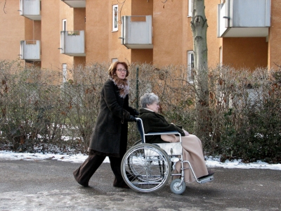 Eine Frau schiebt eine Frau im Rollstuhl