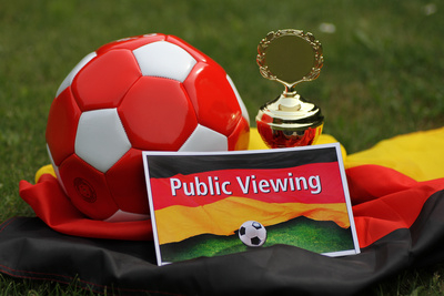 Arrangement von Fußball, Pokal, Deutschlandfahne und Public-Viewing-Karte